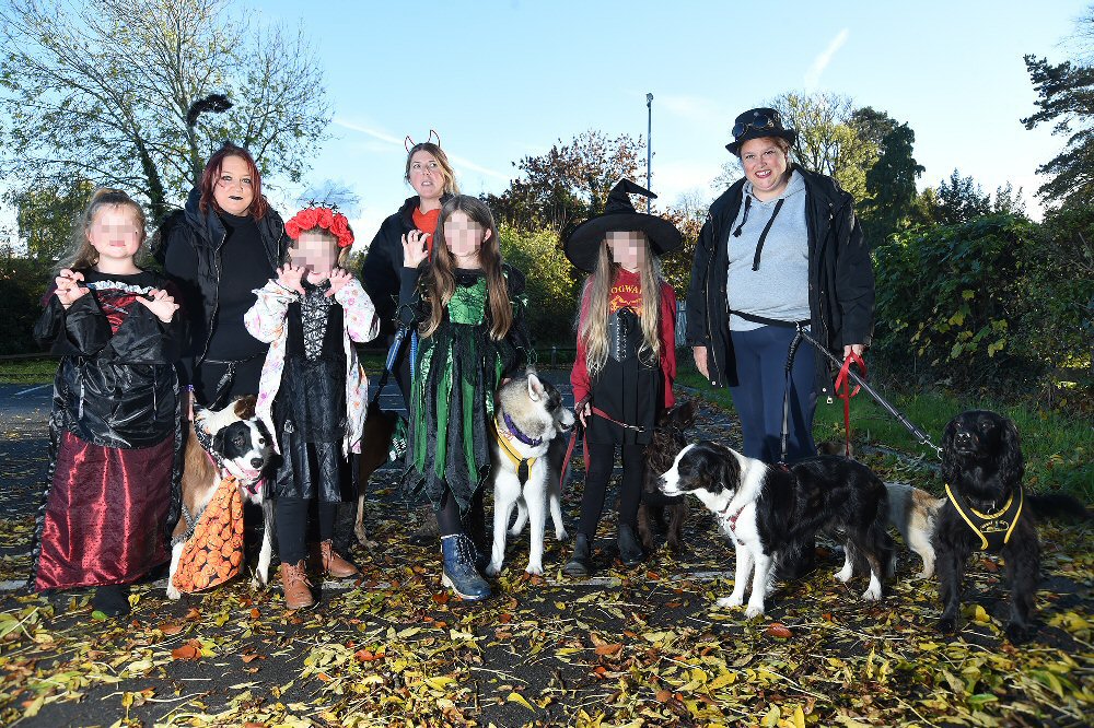 Photograph: Large group of people in Halloween Costumes with black and white dog.